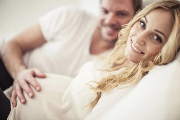 Portrait-of-happy-pregnant-woman-with-man-lying-in-bed